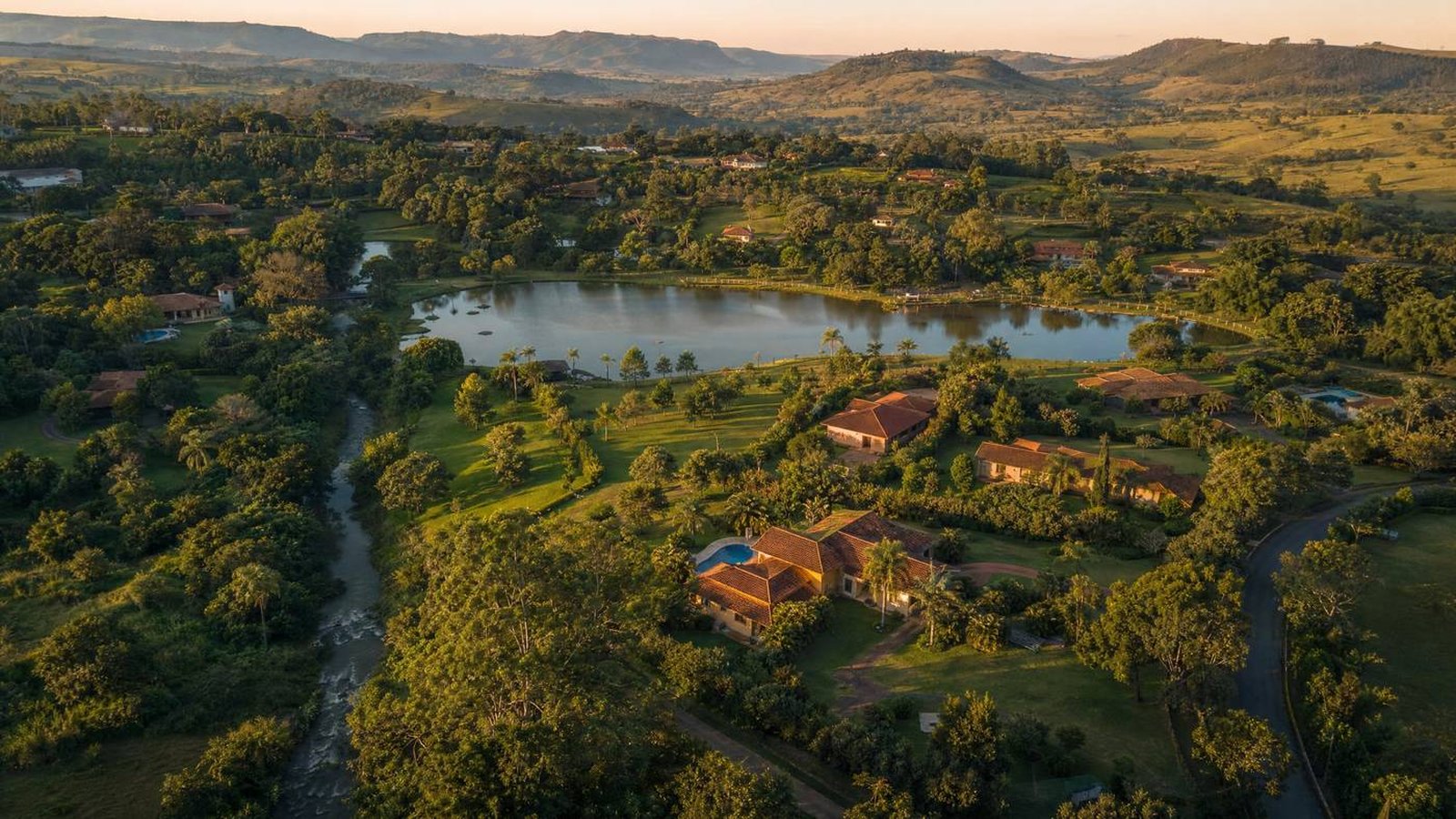Vista aérea de condomínio de chácaras de alto padrão com lago central ao entardecer — constituição e regularização com segurança jurídica